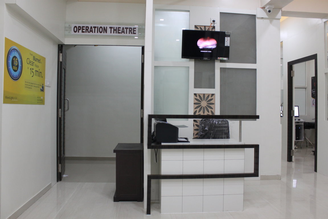 Operation Theatre threshold at Insight Institute, with a frosted-glass door, endoscope-view monitor and an OT-side coordination desk in the foreground